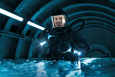 Tom Cruise als Ethan Hunt bis zum Bauch im Wasser stehend in Tauchausrüstung in einem U-Boot.