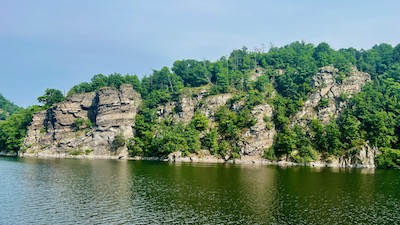 Begrünte Felsen am Rand eines Sees.