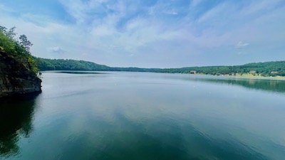Eine ganz glatte riesige ruhige Wasserfläche, am Horizont begrünte Ufer.