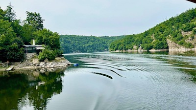 Sanfte Wasserwellen auf einem ruhigen See. Rundum bewaldete niedrige Hänge.