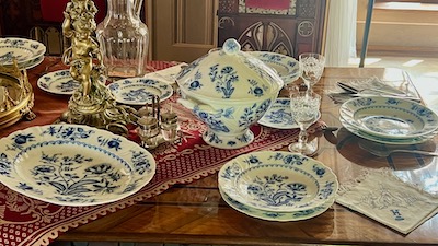 Ein Service von Zwiebelmuster-Porzellan, mit Tellern, Suppentellern, Suppenschüssel, Anrichteplatte, Glaskaraffe und großen Kerzenständer.