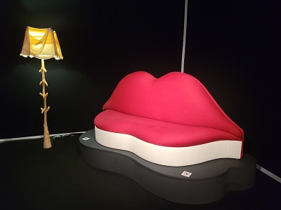 Sofa in Form geschwungener Lippen neben Stehlampe