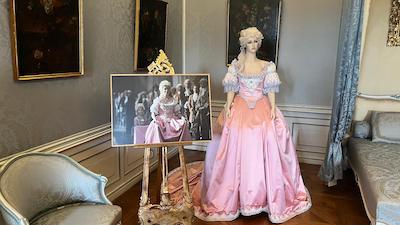 Szenenfoto eines Historienfilms über Maria Theresia mit Marie-Luise Stockinger als junge Maria Theresia, Daneben das Kostüm der Schauspielerin. Im Hintergrund Barockgemälde.
