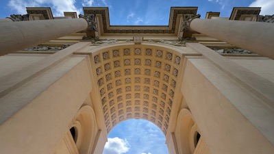 Blick in den Bogen eines Triumphbogen aus der Empire-Zeit und den strahlend blauen Himmel.
