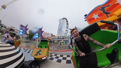 Frau sitzt in einer Gondel vom Break Dance im Prater und lacht.