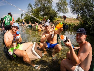 Menschen sitzen mit Wasserpistolen im Fluss Traisen