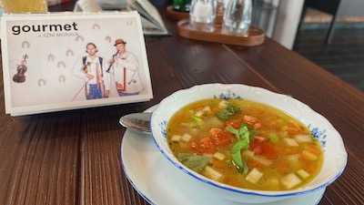 Eine klare Gemüsesuppe mit viel Gemüseeinlage. Daneben ein tschechischer Gourmetführer für Südmähren.