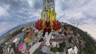 Olivia Schwarz schreit wie sie beim Wiener Freifallturm hinuntersaust. Dahinter der Blick auf den Prater.