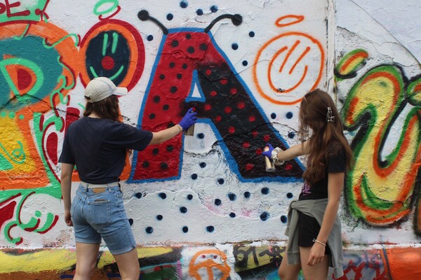Zwei Frauen besprühen in Wien eine Wand mit einem A