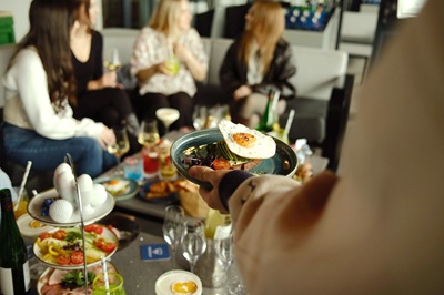 Frau mit Egg Benedict vor einem Tisch mit weiteren Brunchspeisen mit Freundinnen bei Topgolf Wien