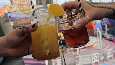 Zwei Hände halten einen Negroni und Tequila Sunrise Cocktail
