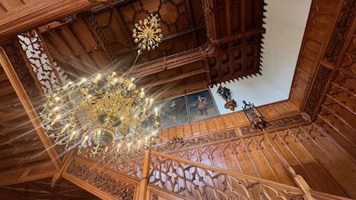Ein holzvertäfeltes Treppenhaus mit einem dreistufigen Messingluster.