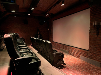 ein 5D Kino mit einem halbdunklen Kinosaal. Boden und Wände aus Ziegelstein, Sitze sind schwarz