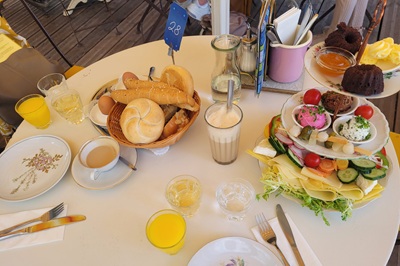 Tisch mit Kaffee, Orangensaft, Gebäck und Erbschleicher Frühstück auf drei Tellern in der Vollpension.