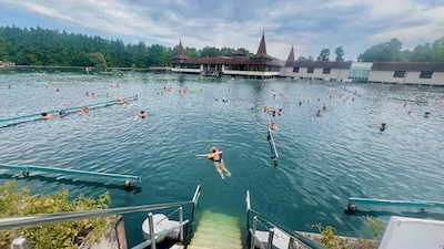 Gesamtblick auf den Thermalsee von Hévíz mit Badehäusern und Badegästen.