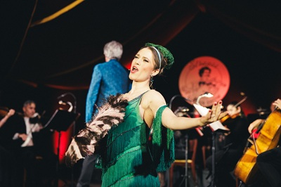 Sängerin in grünem Kleid vor einem Live-Orchester