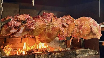 Schweinefleisch dreht sich auf einem Grill.