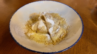 Eine slowakische Lokša mit zerlassener Butter und Staubzucker auf einem weißen Teller.