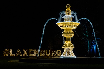 Ein strahlender Lichterbrunnen im Dunkeln. Dahinter der beleuchtete Schriftzug #laxenburg