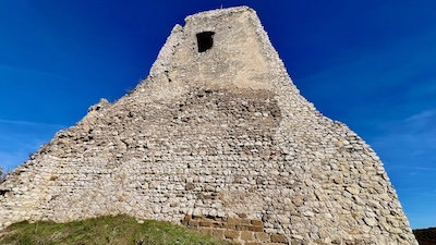 Der Hauptturm von Burg Čachtice in der Slowakei. Ein mächtig aufragender Bau aus Kalkstein mit einer kleinen Fensterluke.