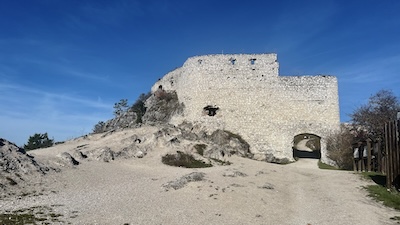 Die Außenmauern des Südflügels der Burgruine Čachtice mit dem Südtor. Die Mauern und der sandig-kalkhaltige Boden sind ganz in weiß.