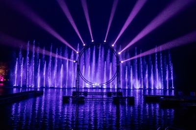 Lila beleuchteter Sprungbrunnen und lila Scheinwerfer am Burgteich im Schlosspark Laxenburg.
