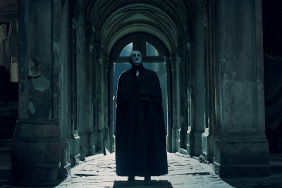 Maskierte Gestalt in schwarzer Kleidung in einer dunklen Passage