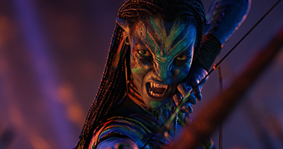 Zoe Saldaña spannt als als Neytiri im finalen Kampf von Avatar 3 ihren Bogen und zeigt kampfeslustig die Zähne