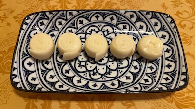 Slowakischer Brühkäse Parenica in der Minitaturform pareničky auf einem blau-weißen, rechteckigen Teller.