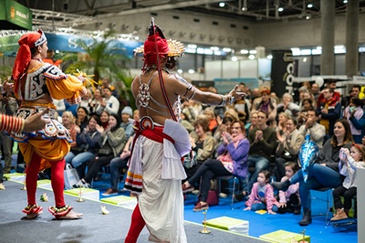 Tänzer vor sitzendem Publikum auf der ReiseArena-Bühne in der Messe Wien Halle