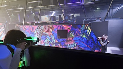 Blick über die Lasertag-Halle im Prater: Eine Lasertag-Spielerin in erhöhter Position von unten phasert eine Angreiferin.