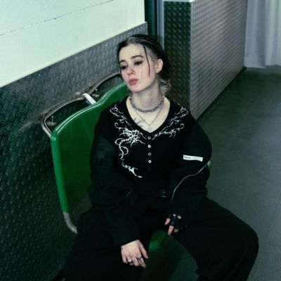 Sängerin Ness sitzt auf einem grünen Sessel