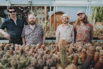 Reverend Stomp umringt von Kakteen in verschiedensten Größen