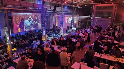 METABowl SuperBowl Party in der METAstadt. Leute beim Essen auf der 2. Etage mit Blick auf den Riesen-Screen