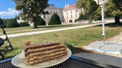 Ein Stück Esterházy-Torte im Schanigarten des Schlosscafés von Schloss Esterházy in Fertöd mit Blick auf das Schloss.