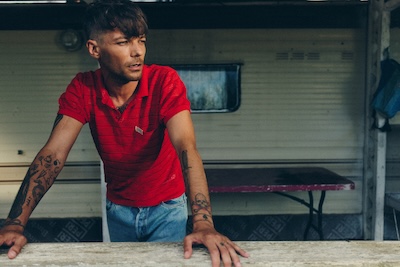 Ex-One-Direction Sänger Louis Tomlinson lehnt an einem Tisch