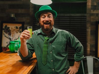 Man mit St. Patrick's Day Outfit und Shotglas in der Hand