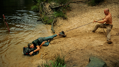 Standbild aus dem Netflix-Film Apex: Ein Mann zieht eine am Fuß gefesselte Frau aus dem Wasser