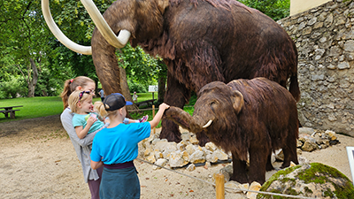Familie vor Mamut-Modellen beim MAMUZ Schloss Asparn