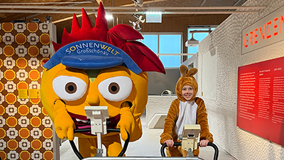 SONNENWELT Maskottchen Solarix und Kind im Osterhasen-Kostüm lächeln in die Kamera