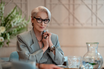 Meryl Streep sitzt in grauem Anzug an einem Tisch mit Gläsern im Film Der Teufel trägt Prada 2