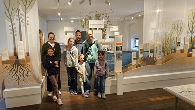 Zwei Familien stehen zwischen einem Modell der Donau-Auenlandschaft bei der Ausstellung Im Fluss