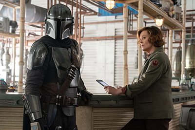 Der Mandalorian (Pedro Pascal) und Colonel Ward (Sigourney Weaver) besprechen in einer Bar die nächste Taktik (c) Walt Disney