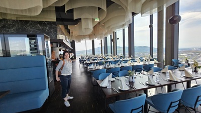 Frau steht vor gedeckten Tischen im Rooftop-Restaurant Q27 mit Blick auf Linz