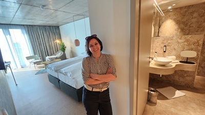 Frau steht im Themenzimmer A Mindful Space. Im Hintergrund ist das Schlafzimmer und das Bad zu sehen.