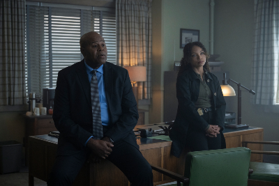 Chi McBride und Logan Browning sitzen auf einem FBI-Schreibtisch
