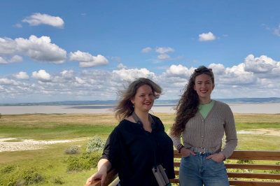 zwei Frauen auf Aussichtsplattform, im Hintergrund der Neusiedler See mit Schilfflächen bei blauem Himmel