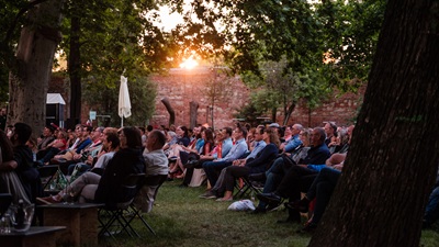 Besucher:innen von THEATER IM PARK sitzen in der Abendsonne im Schwarzenberggarten