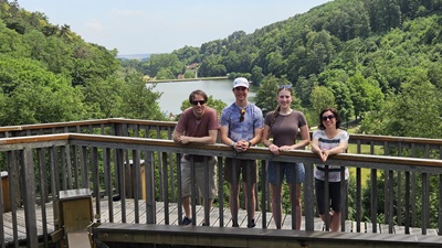 Zwei Männer und zwei Frauen auf dem Holzturm der NaturArena Geschriebenstein - im Hintergrund der Badesee Rechnitz