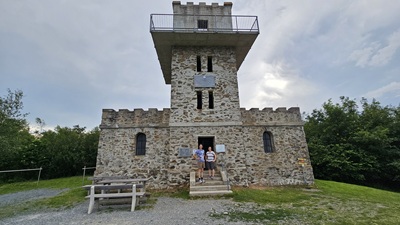 Man und Frau stehen auf der Stufe vor der Aussichtswarte Geschriebenstein